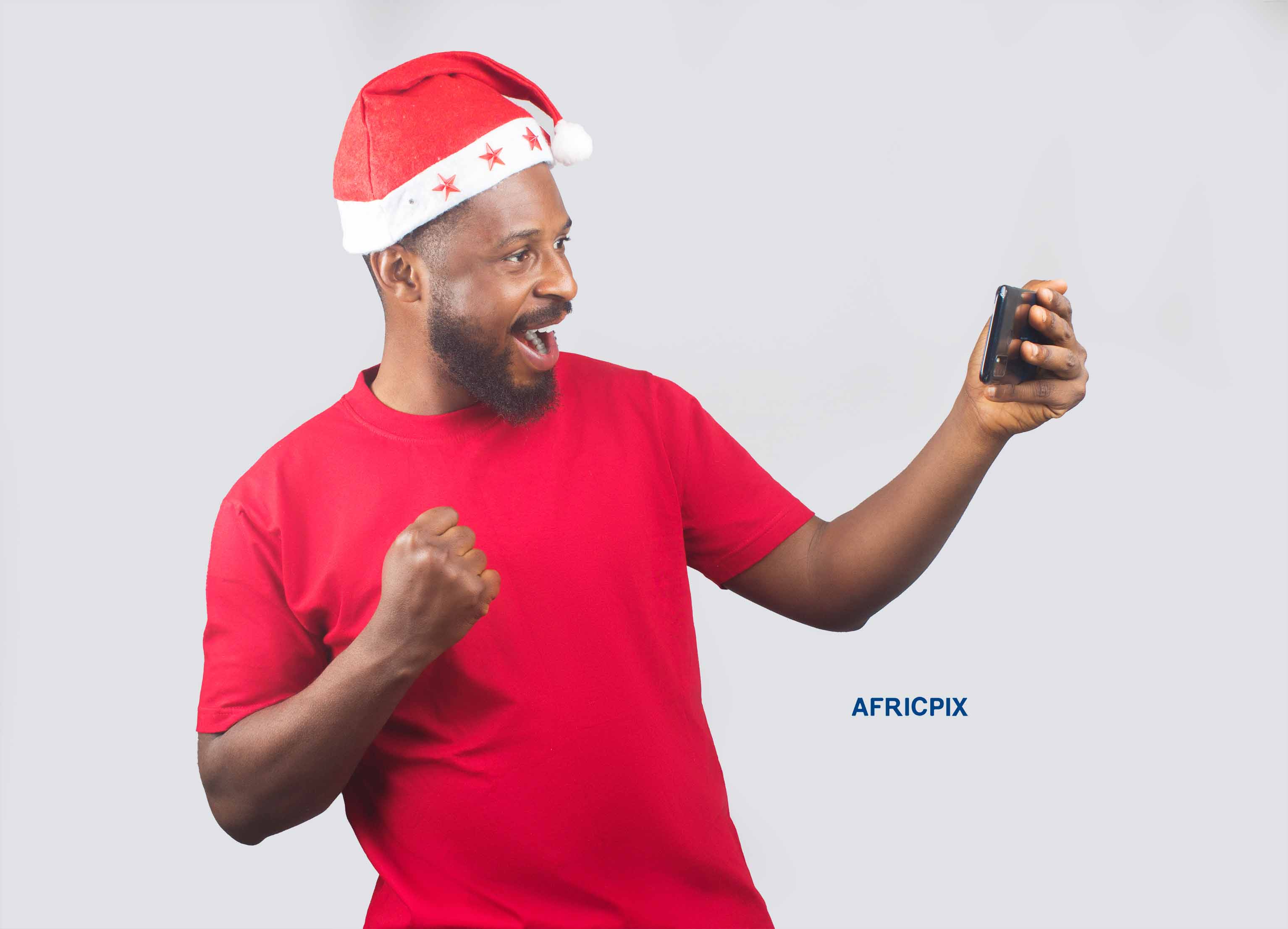 An African Nigerian man wearing a Christmas cap, holding a phone in one hand and pointing at it with the other hand 5.